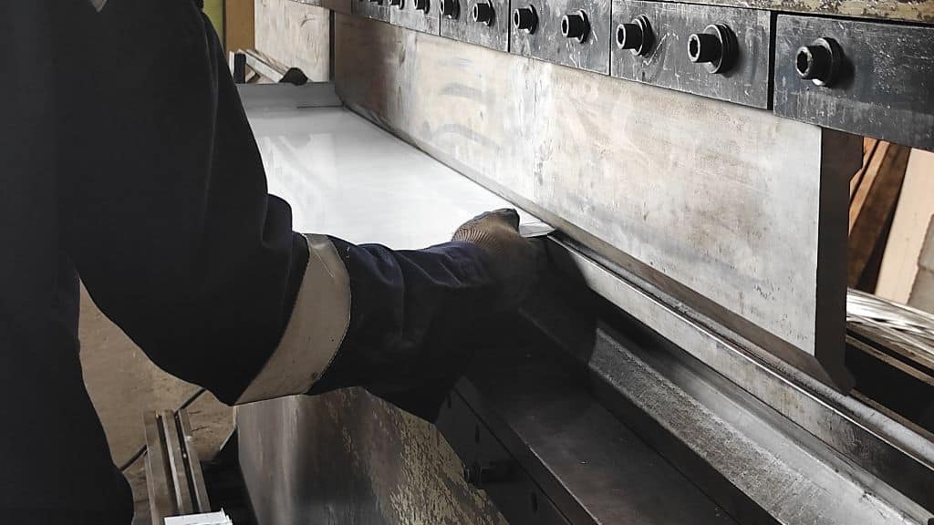 Närbild av verkstadsarbetare som bockar plåt i en plåtbearbetningsmaskin